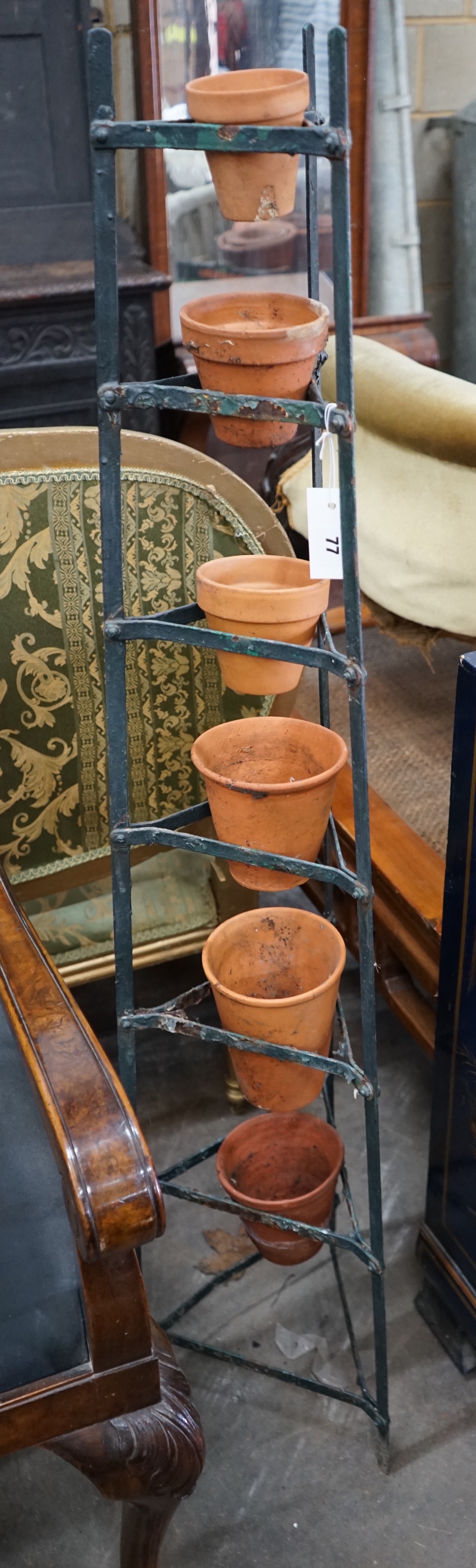 A wrought iron six tier pot stand, together with six terracotta pots, height 143cm